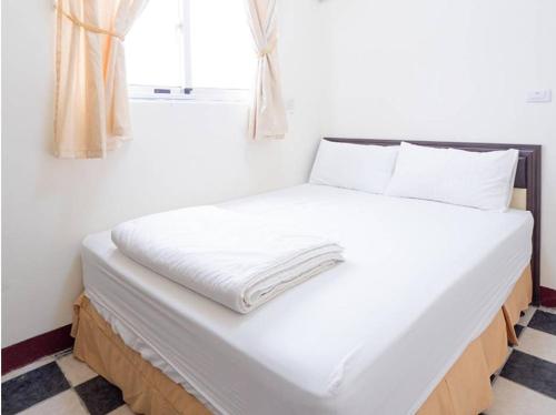 a bed with white sheets and a window in a room at 好宿民宿 in Jinning