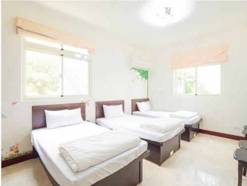 three beds in a room with white walls and windows at 好宿民宿 in Jinning