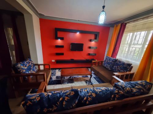 a living room with a couch and a red wall at OCTA HOMES in Kampala