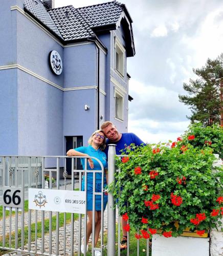 a man and woman leaning on a fence in front of a house at Villa Blue Mare in Ustronie Morskie