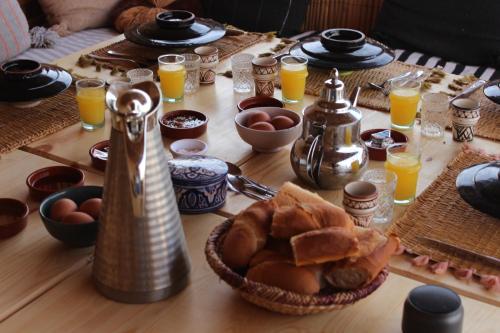 a wooden table topped with a table with food and orange juice at Sable beach surf camp taghazout in Taghazout