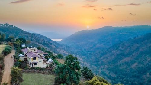 a house on a hill with the sunset in the background at Courtyard Villa by Hillstaytion,com in Panchgani