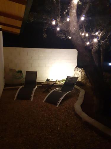 two chairs sitting next to a tree at night at Bungalow Sierra San Vicente in Hinojosa de San Vicente