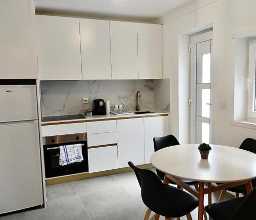 a kitchen with white cabinets and a table with chairs at Cantinho do Castelo in Bragança