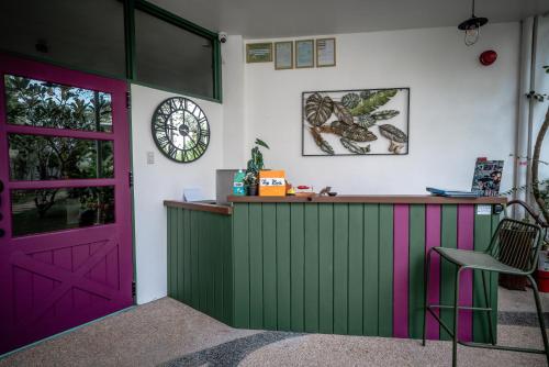 a bar with a pink and green door and a clock at Tana Mysterious garden in Panglao
