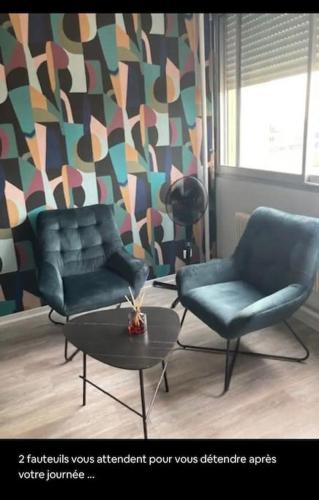 a living room with two chairs and a table at Studio centre-ville in Montceau-les-Mines