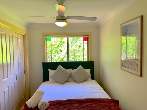 a bedroom with a bed with white sheets and a window at Oasis 5 Bedroom Charming House in Sydney