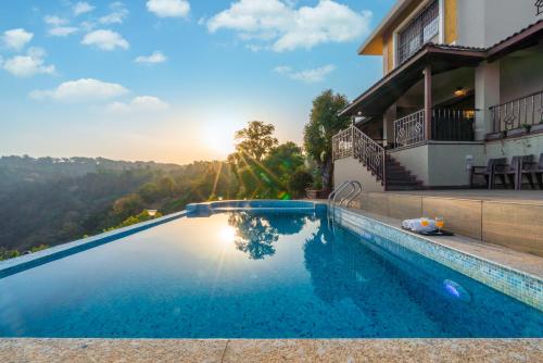 una piscina frente a una casa con puesta de sol en Courtyard Villa by Hillstaytion,com, en Panchgani