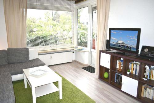 - un salon avec un canapé et une télévision dans l'établissement Carpe Diem Ferienwohnung Nr 97, à Niendorf