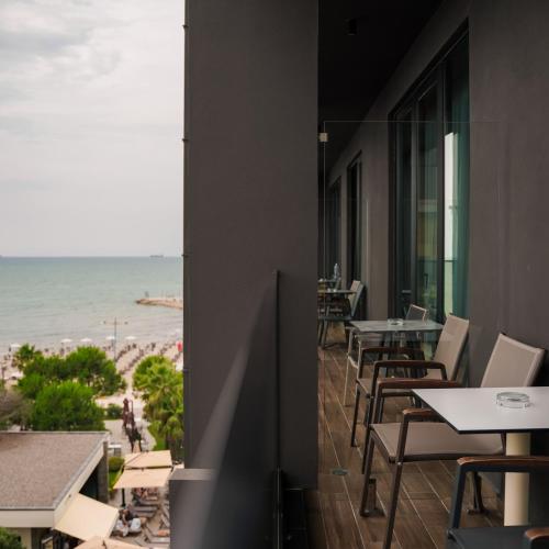 a balcony with tables and chairs and the ocean at Supreme Hotel in Golem