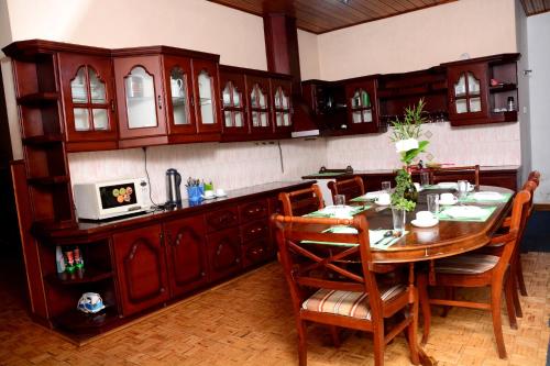 een keuken met een houten tafel en stoelen in een kamer bij The West Gate Bungalow in Nuwara Eliya