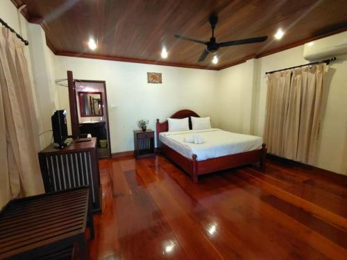 1 dormitorio con 1 cama y ventilador de techo en somvang khily guesthouse 宋旺吉利 酒店, en Luang Prabang