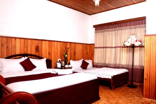 ヌワラエリヤにあるThe West Gate Bungalowのベッド2台と窓が備わるホテルルームです。