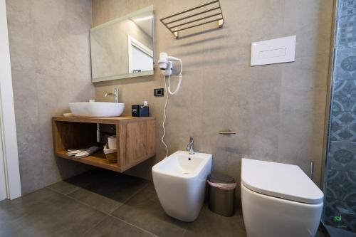 a bathroom with a sink and a toilet and a mirror at New River Hotel in Borgetto