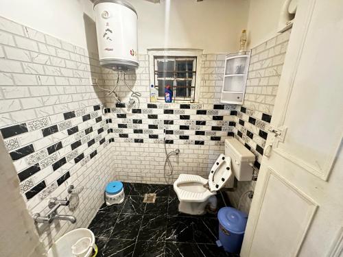 a bathroom with a black and white tiled wall at The Forest Way Loft by YEMBERZAL in Srinagar