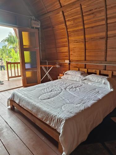ein großes Bett in einem Zimmer mit einer Holzwand in der Unterkunft LBA chalet in Balik Pulau