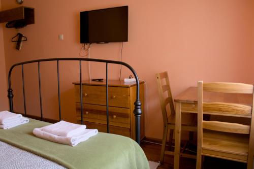 a bedroom with a bed and a table and a television at Gościniec Koćmierzów in Sandomierz