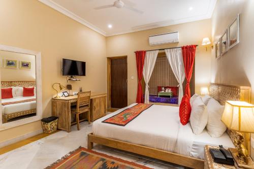 a bedroom with a bed and a desk with a computer at Hotel Jasmin Home in Jaisalmer