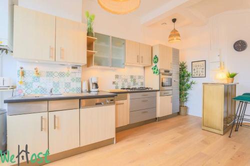 a large kitchen with white cabinets and a table at La porte verte, superbe triplex 16P in Arras