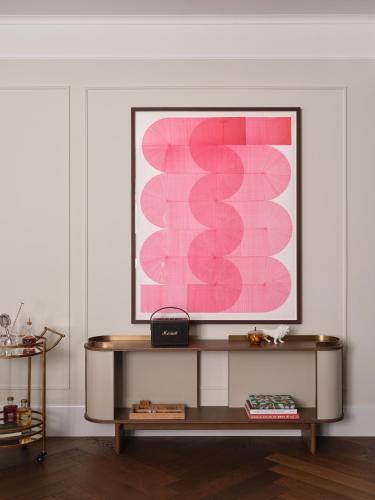 a living room with a table with a pink painting on the wall at Rosewood Munich in Munich