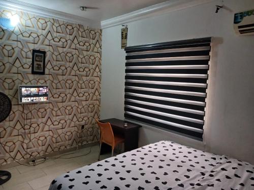 a bedroom with a bed and a window and a desk at Arsenal's Lodge in Abuja
