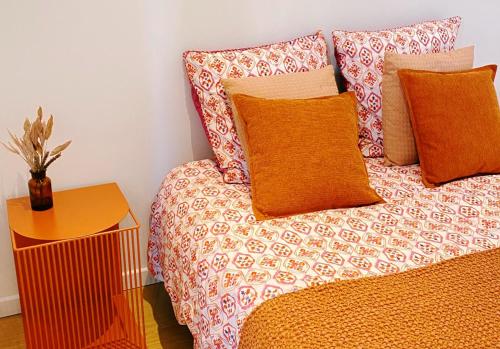 a bed with orange pillows and a table with a plant on it at Le Bohème ⸱ Stationnement gratuit ⸱ Fibre in Déols