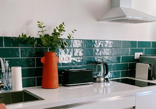 a green tiled kitchen with an orange vase on the counter at Le Bohème ⸱ Stationnement gratuit ⸱ Fibre in Déols