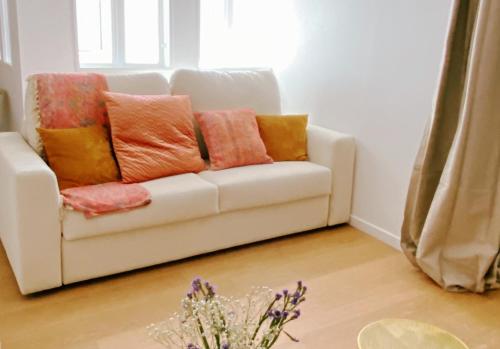 a white couch with colorful pillows in a living room at Le Bohème ⸱ Stationnement gratuit ⸱ Fibre in Déols