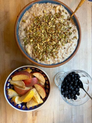two bowls of oatmeal with fruit and a bowl of black berries at Bellinge House in Horreby