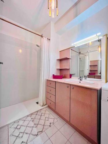 une salle de bain avec un lavabo et un grand miroir dans l'établissement L'Eden : Apt 4 Prs, clim, parking,300 m des plages, à Antibes