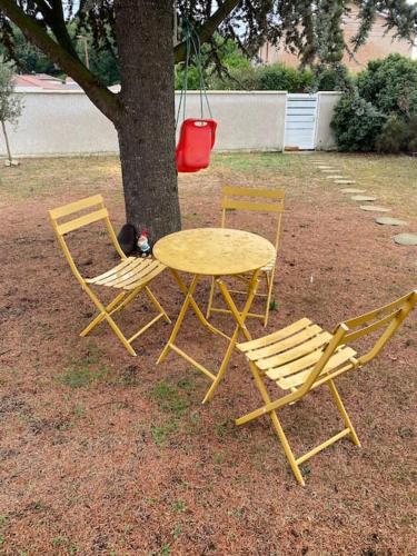 Deux chaises, une table et deux chaises autour d'un arbre dans l'établissement Appartement Cosy Villieu, à Villieu