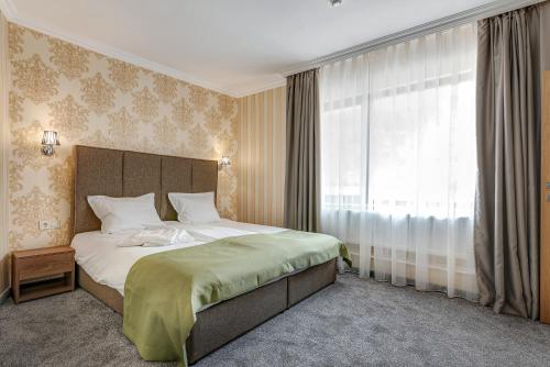 ein Schlafzimmer mit einem großen Bett und einem Fenster in der Unterkunft Къща за гости Чудните Мостове in Zabŭrdo