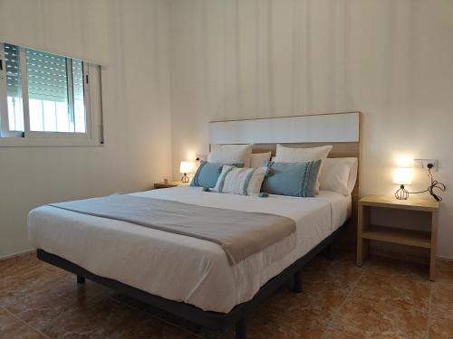 a bedroom with a large bed with blue pillows at La caseta del canal in Deltebre