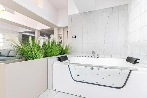 biała łazienka z wanną i roślinami w obiekcie ForS Resort & Spa w Belgradzie