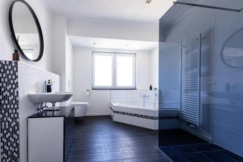 a bathroom with a tub and a sink and a toilet at Design Apartment zentral für 6 in Andernach: Ausblick, WiFi, Küche in Andernach