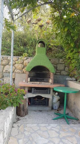 a green oven with a bench and a table at Apartmani Roza Lopar in Lopar