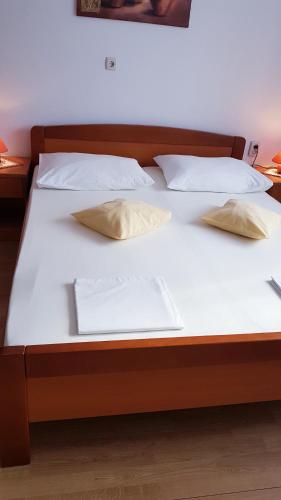 a bed with white sheets and pillows on it at Apartmani Roza Lopar in Lopar