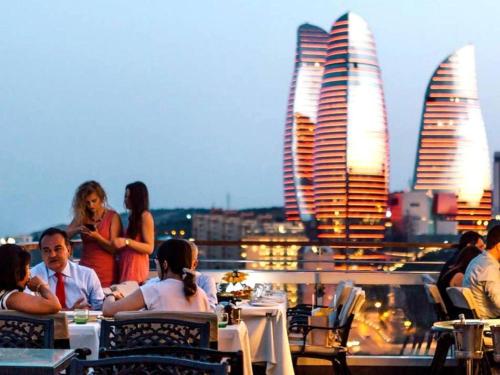 a group of people sitting at tables on top of a building at Lara Hotel and Spa in Baku