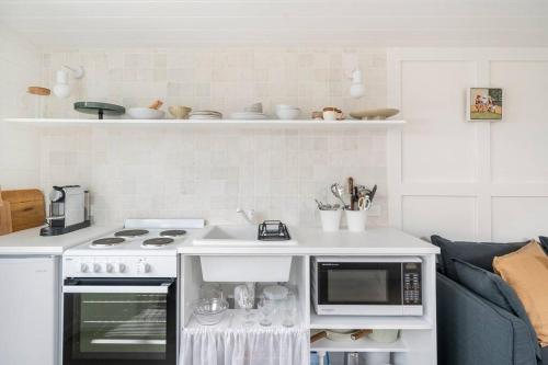 a white kitchen with a stove and a microwave at George @ Ethel & Odes in Bundeena