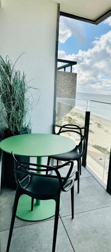 a green table and chairs on a balcony with the beach at Middelkerke Volledig gerenoveerd appartement met zeezicht in Middelkerke