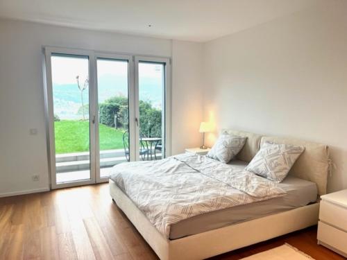 a white bedroom with a bed and a balcony at Modernes Apartment an Traumlage in Lugano mit Seesicht in Paradiso