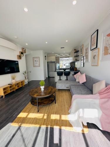 a living room with a couch and a table at Plush 3 bedroom property in Hobsonville in Auckland