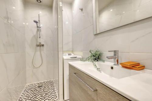 a white bathroom with a shower and a sink at Typical Chic Parisian Flat-Near les Champs-Élysées in Paris