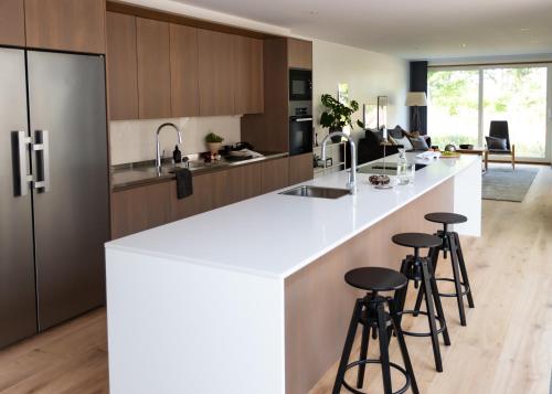 a kitchen with a white counter top and bar stools at Halltorp Townhouse in Borgholm