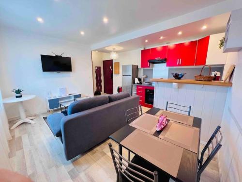 un salon avec un canapé et une cuisine avec des armoires rouges dans l'établissement Le Red Light : Apt 4 Prs, Clim, 300m des plages, à Antibes