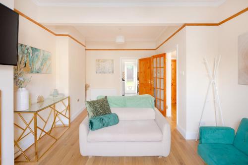 sala de estar con sofá blanco y silla azul en Stylish House in Wimbledon en Londres