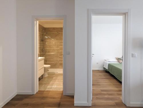 a bedroom with a bed and a bathroom with a shower at Canary's Suite in Matosinhos