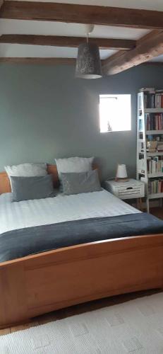 a bedroom with a large bed and a book shelf at Chambre double dans la maison de Pauline et Stéphane in Hommarting