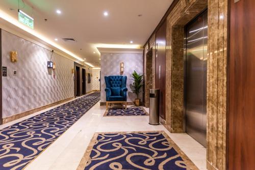 a hallway with a blue chair in a hotel lobby at Paradise Inn Jeddah Hotel in Jeddah