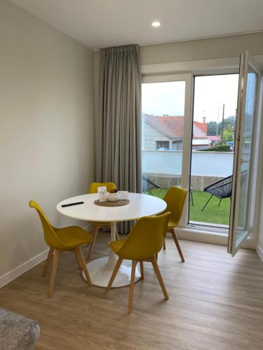 a dining room with a white table and yellow chairs at Apartamentos TARELA Porriño in Porriño